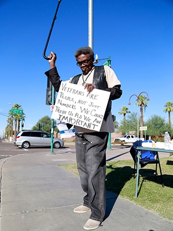 Wallace J. Brown Sr. waves his cane at honking cars passing by in support of a veterans rally at the Phoenix VA Medical Center on Monday, Nov. 9, 2015.  He said he had hoped President Obama's visit back in March would have led to improvements in patient care. (Photo by April Morganroth/Cronkite News)