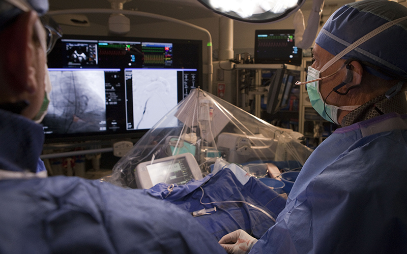 Cardiologist Timothy Byrne and his team look into the monitor while feeding a catheter into the heart chamber. (Photo by Brian Thorsen/TAVR Abrazo Arizona Heart Hospital)