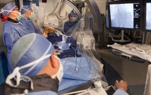 Team of cardiologists and cardiac surgeons look into the monitor while preforming heart surgery. (Photo by Brian Thorsen/TAVR Abrazo Arizona Heart Hospital)