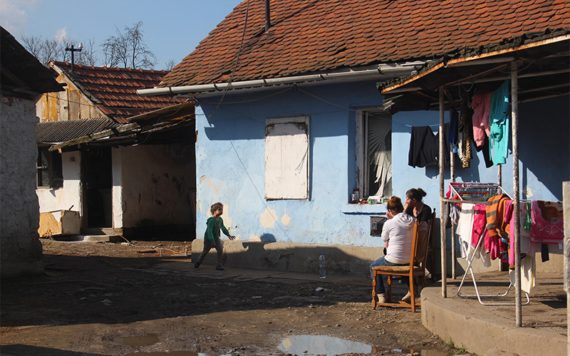 A Roma girl runs to two women as they sit and talk in one of the Roma neighborhoods of Sajókaza, Hungary. 