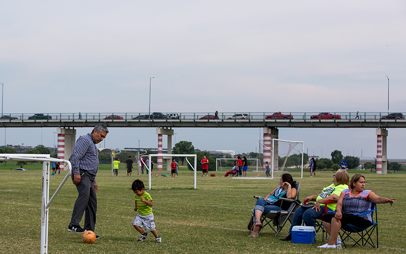 Calai Hernández (third from right) watches her son's soccer team practice at Shelby Park in Eagle Pass. Behind them is the International Bridge that connects Eagle Pass Texas to Piedras Negras, Coahuila.