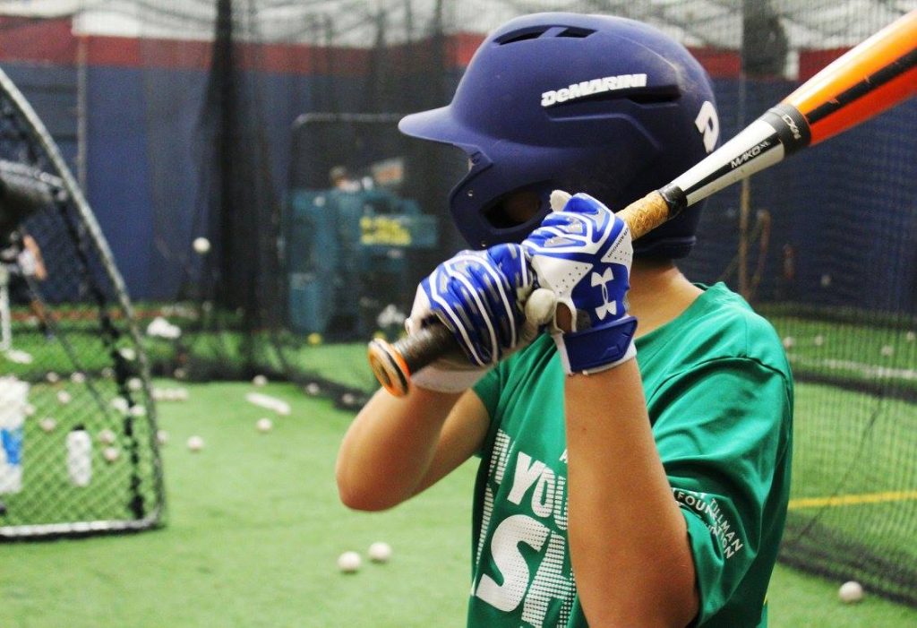A young athlete takes batting practice in a cage with Chad Moeller. (Photo by Trisha Garcia/Cronkite News)