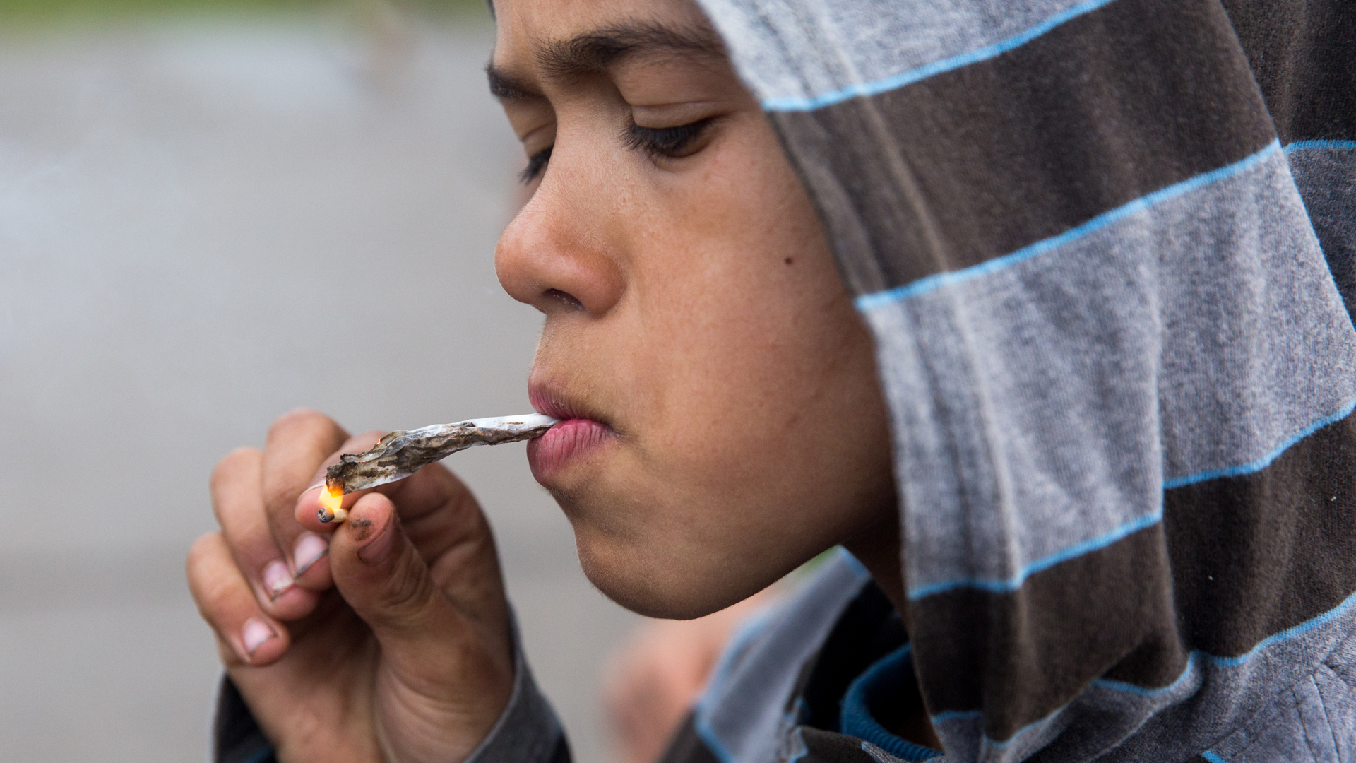 A primary school age Roma boy lights a handrolled cigarette. (Photo by Courtney Pedroza)