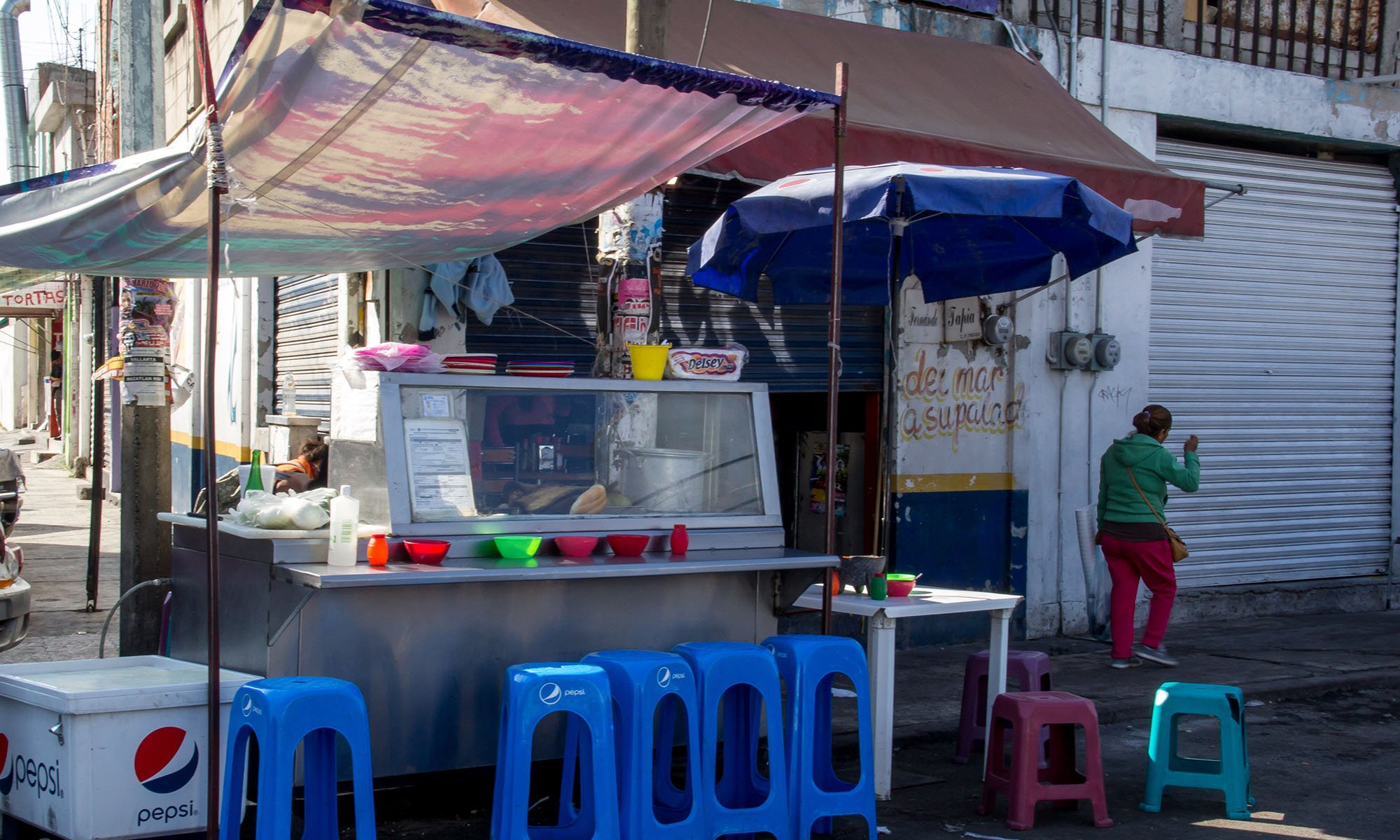 A local woman passes by Karla Agullon’s taco stand called “Tacos el knockout” (“The Knockout”), which is located in Mercado General Escobedo, the oldest market in Santiago de Querétaro.