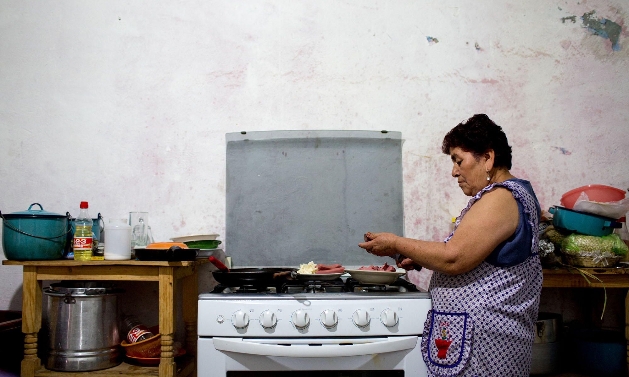 Rodriguez makes lunch for her family in the town of Caleras, Mexico. Her son has been in the United States for over 20 years, in San Antonio. He is an undocumented worker and she worries for his safety after seeing news stories and hearing from people who have been deported. She doesn’t want him to be separated from his daughters. He first left at age 16, came back home then left for good two years later. “He always had that idea that he should help us. We work to survive. That’s why he left. He said, ‘I’m leaving so I can help you,’” Rodriguez said. (Photo by Courtney Pedroza/Cronkite Borderlands Initiative)