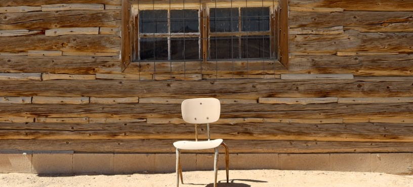 old wooden chair in front of wood building