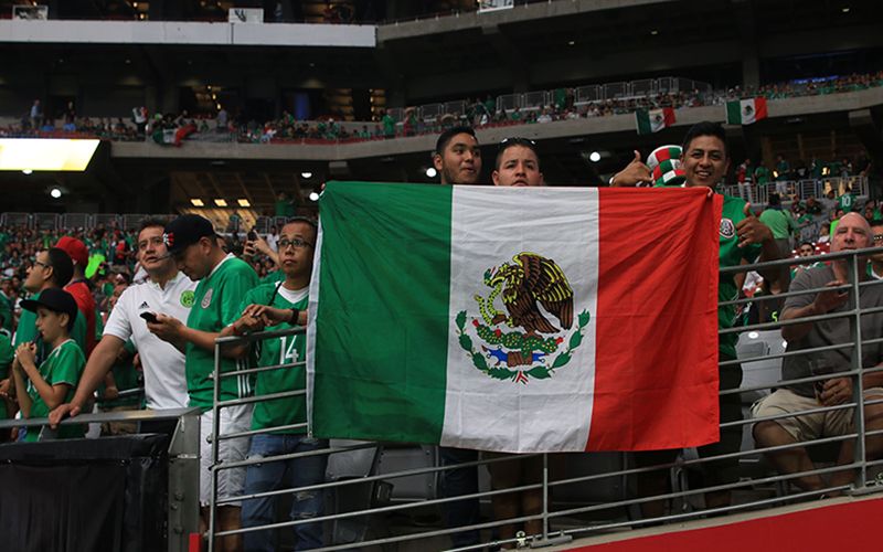 Supporters of the Mexican National Soccer Team pose with the Mexican flag just before the start of the game.