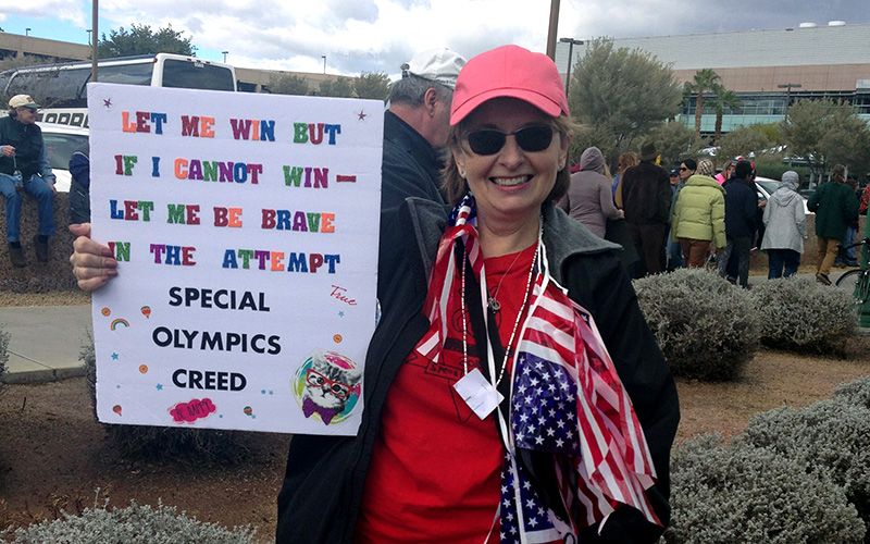 Former special education teacher Elizabeth Holmes, 54, holds a poster to showcase Special Oolympic students. (Photo by Saundra Wilson/Cronkite News)