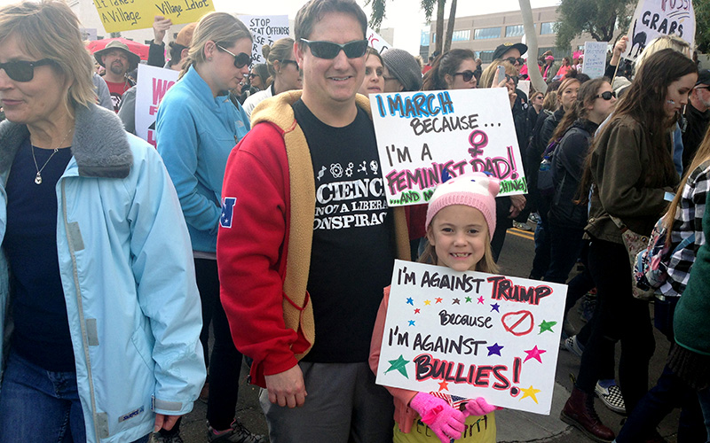 Gilbert father Casey Knapp, 38, stands with his 7-year-old daughter, who made her own sign. (Photo by Saundra Wilson/Cronkite News)
