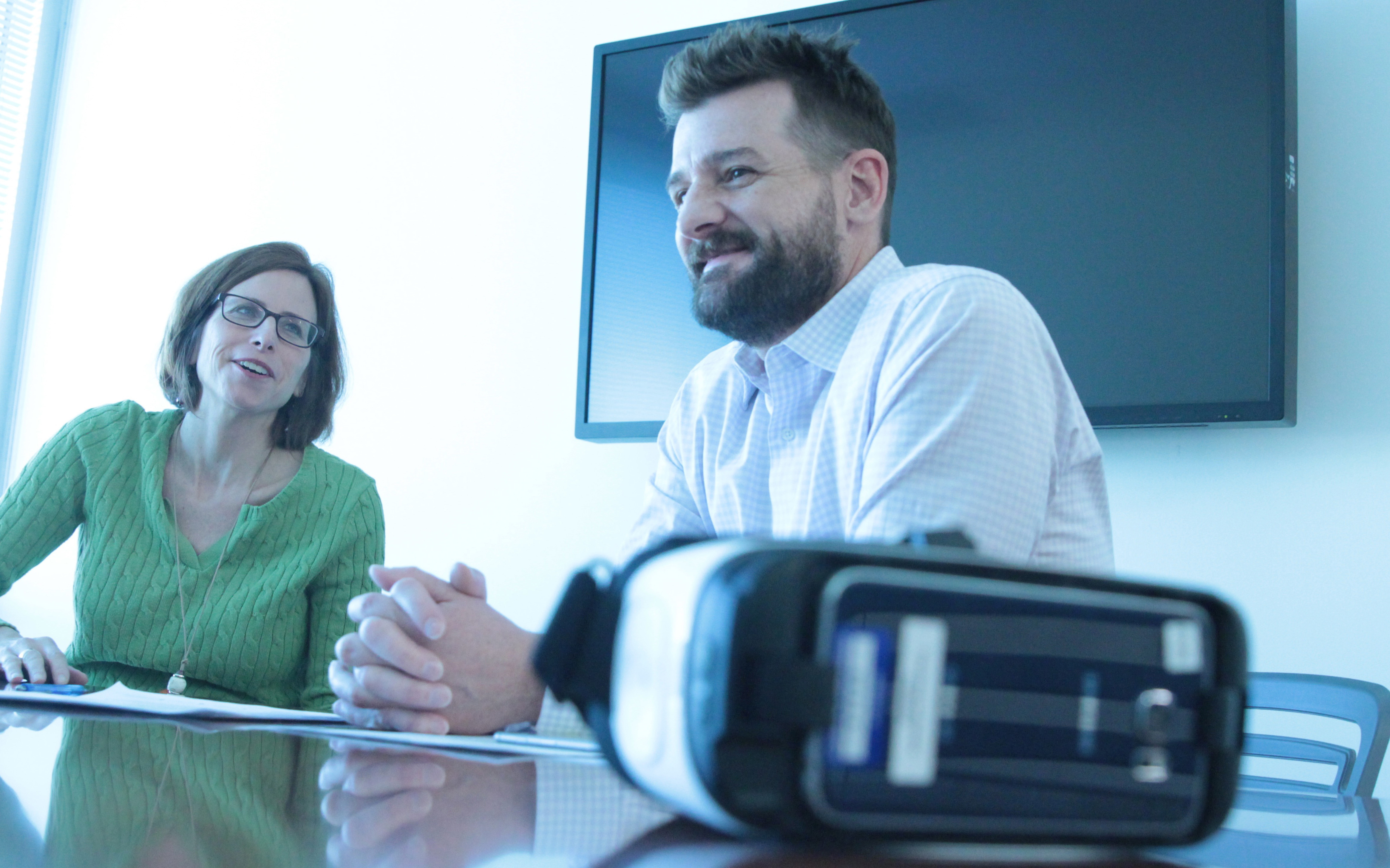 Jamie Daer and Scott Dunn with the Arizona Office of Tourism discuss their virtual reality experience, which simulates mountain biking in Sedona and skydiving at the Grand Canyon. (Photo by Erica Apodaca/Cronkite News)