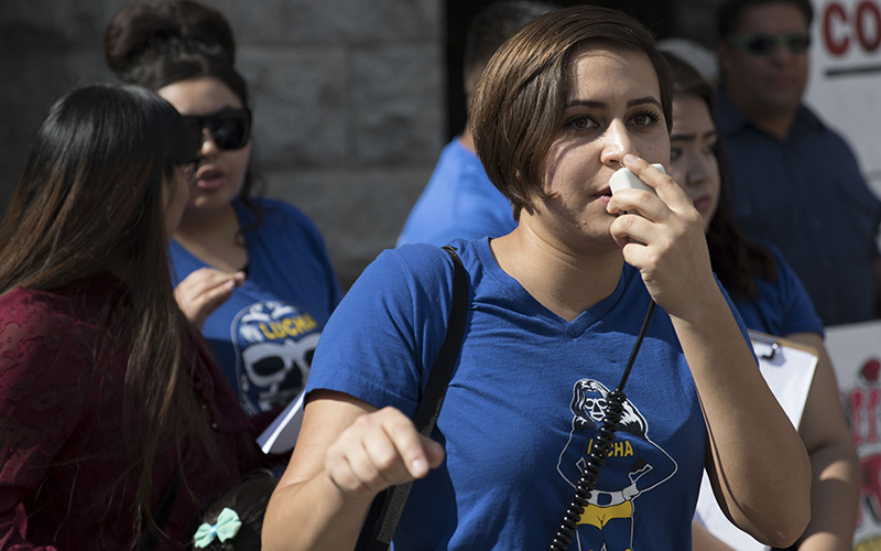 Immigration activist Nicole Hale talks in the megaphone, her voice roaring over the noise of the crowd in front of her. Hale says events like this demonstration are important to engage people into the LUCHA movement via social media. (Photo by Josh Orcutt/Cronkite News)