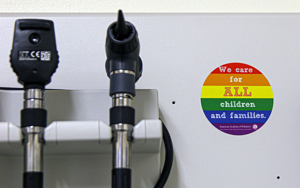 A medical office has a rainbow sticker that reads: "We care for ALL children and families."