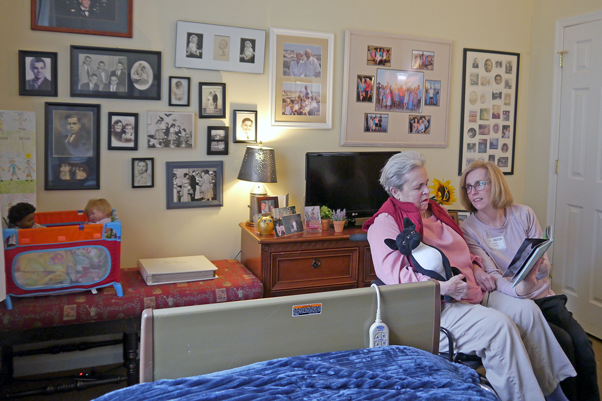 Bridget Schmidt reads a picture book to her mother, Pat Rush, who was diagnosed with Alzheimer’s disease in 2016. The Schmidt family was physically separated from Rush for months during the pandemic, which took an especially grave toll on the elderly and those with dementia. (Photo by Emily Schmidt/Cronkite News)
