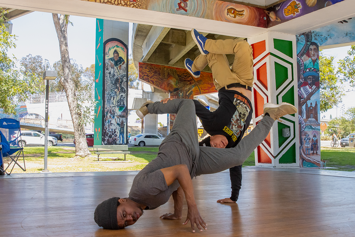 As the sounds of hip hop and soul music vibrate through Chicano Park in San Diego, friends Robert Jones and Ramon Farias practice breakdancing together for the first time in years. The pair were a part of a breakdancing group in high school. “We hope to keep this up and see each other more often, too,” Farias says. (Photo by Lauren Lively/Cronkite News)
