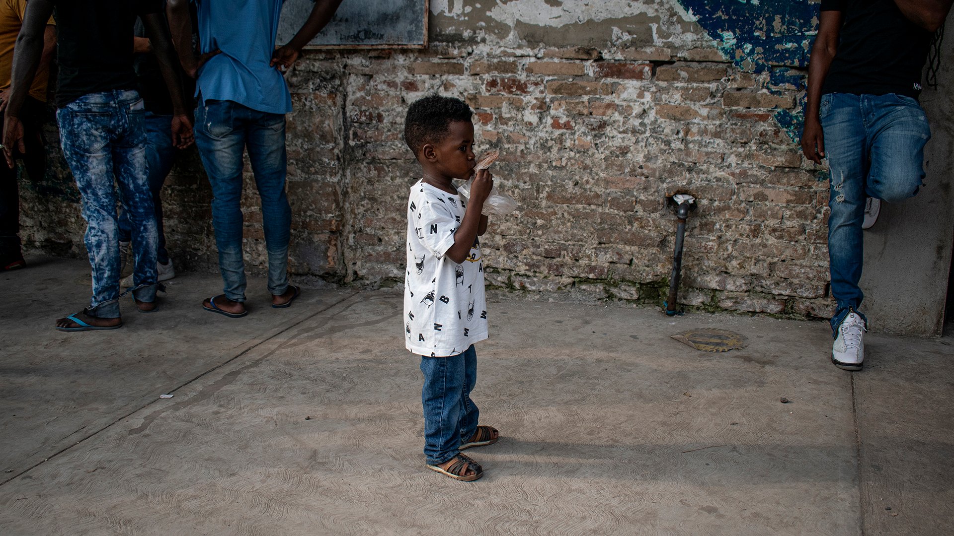A young boy lines up with his family outside the refugee assistance office in Tapachula, Mexico, on March 9. Later in the day, a protest erupted outside the office, with dozens of migrants demanding their paperwork be expedited. (Photo by Juliette Rihl/Cronkite Borderlands Project)
