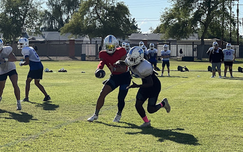 Chandler junior quarterback Dylan Raiola hands off to running back Ca’lil Valentine at a recent practice. Raiola, who is committed to Ohio State, leads the 7-0 Wolves against Basha (6-1) Friday. (Photo by Cole Topham/Cronkite News)