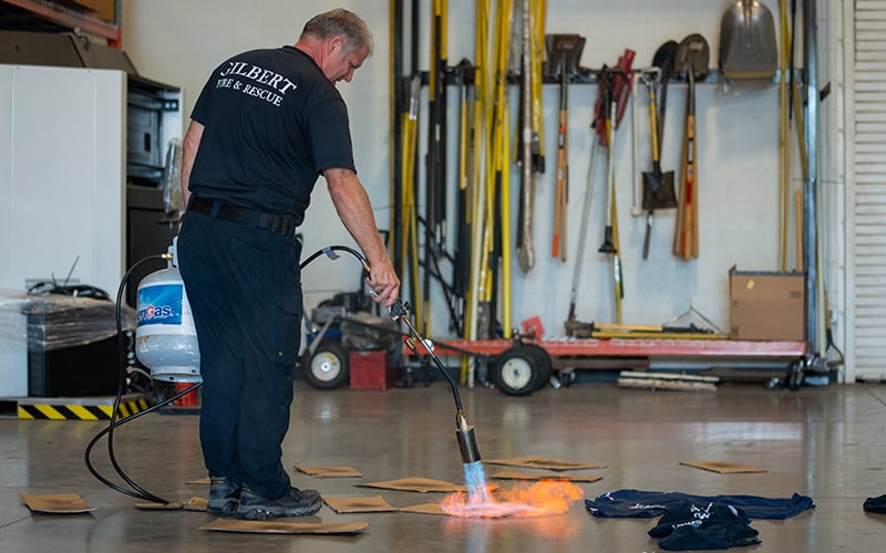 Gilbert fire investigator David Zehring burns cardboard and T-shirts to simulate a fire investigation for Zeta, his arson dog. The black Labrador trains twice a day – even on holidays. (Photo by Samantha Chow/Cronkite News)