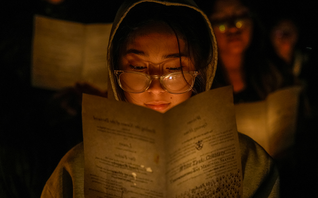 Maria Ornelas, 14, looks at a program during an annual Thanksgiving Eve vigil at White Tanks Cemetery in Litchfield Park on Nov. 23, 2022, organized by André House of Arizona. (Photo by Samantha Chow/Cronkite News)
