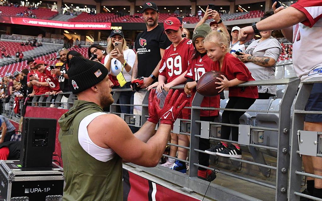 Arizona Cardinals defensive end J.J. Watt plays catch with a young fan in the stands before a recent game against the Seattle Seahawks at State Farm Stadium. One study said the team provides the most affordable fan experience in the NFL. (Photo by Norm Hall/Getty Images)