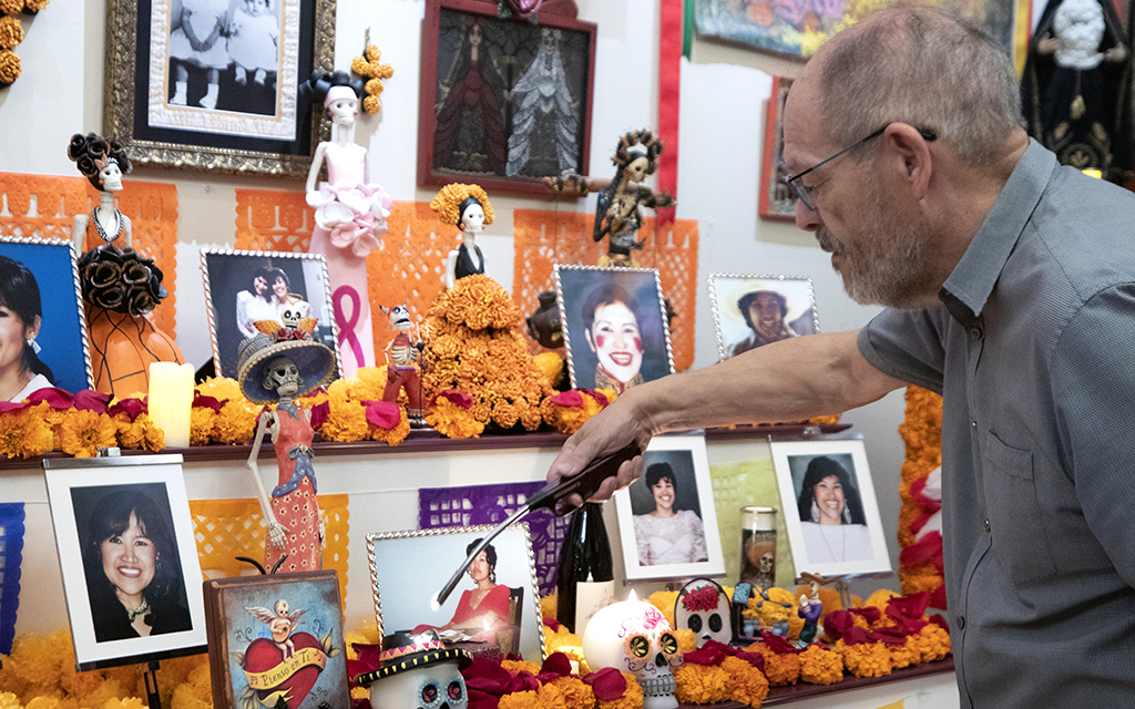 José Cárdenas of Chandler lights candles on Oct. 30, 2022, on one of the altars he built for his wife, Virginia, who died 10 years ago. (Photo by Scianna Garcia/Cronkite News)