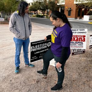 Election Protection Arizona volunteers set up signage outside the Knights of Pythias in Tempe to let voters know to report any issues they might have while voting.  (Photo by Isabel Garcia/Special for Cronkite News)