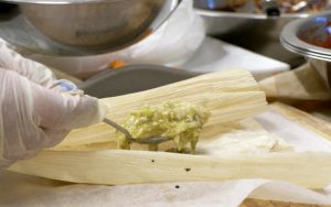Imelda Hartley rellena la masa de un tamal con una salsa verde picante. Este es el tamal "Hope" uno de los más solicitados por su clientela. (Foto de Jimena Vera/Cronkite Noticias)
