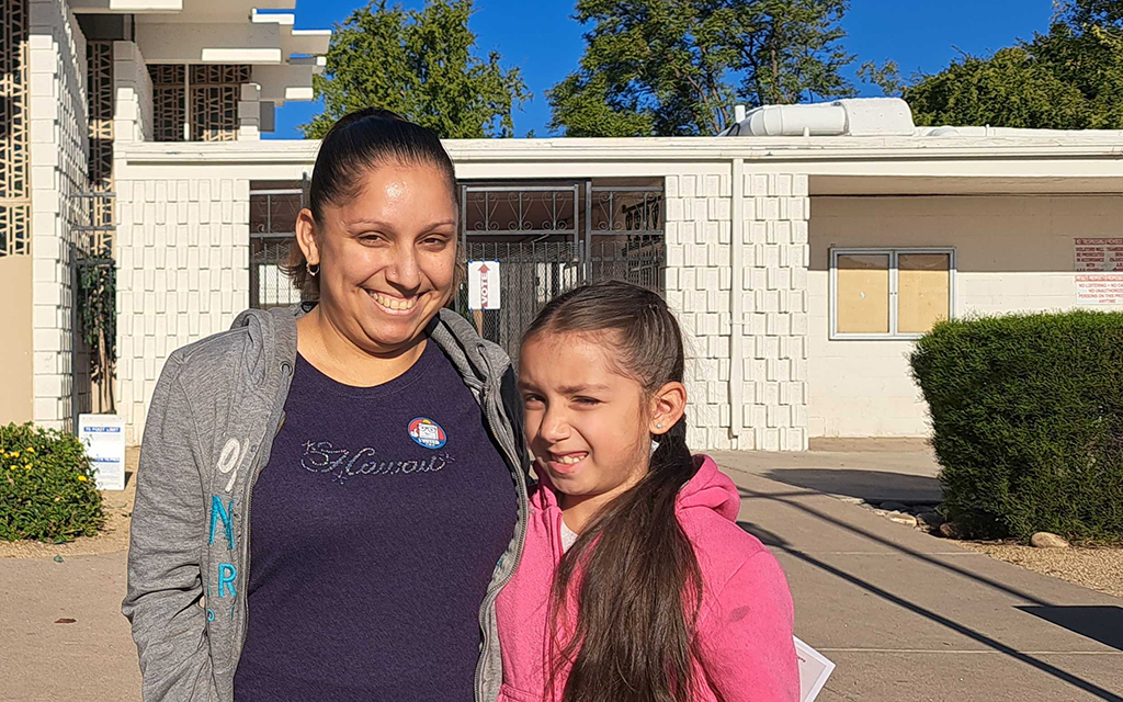 Victoria Medina, right, tags along with her mother Vanessa Figueroa to the polls on Tuesday. This is Victoria's first time going to a polling place, and her mother thought it would be a valuable experience. (Photo by Shelby Rae Wills/Special for Cronkite News)