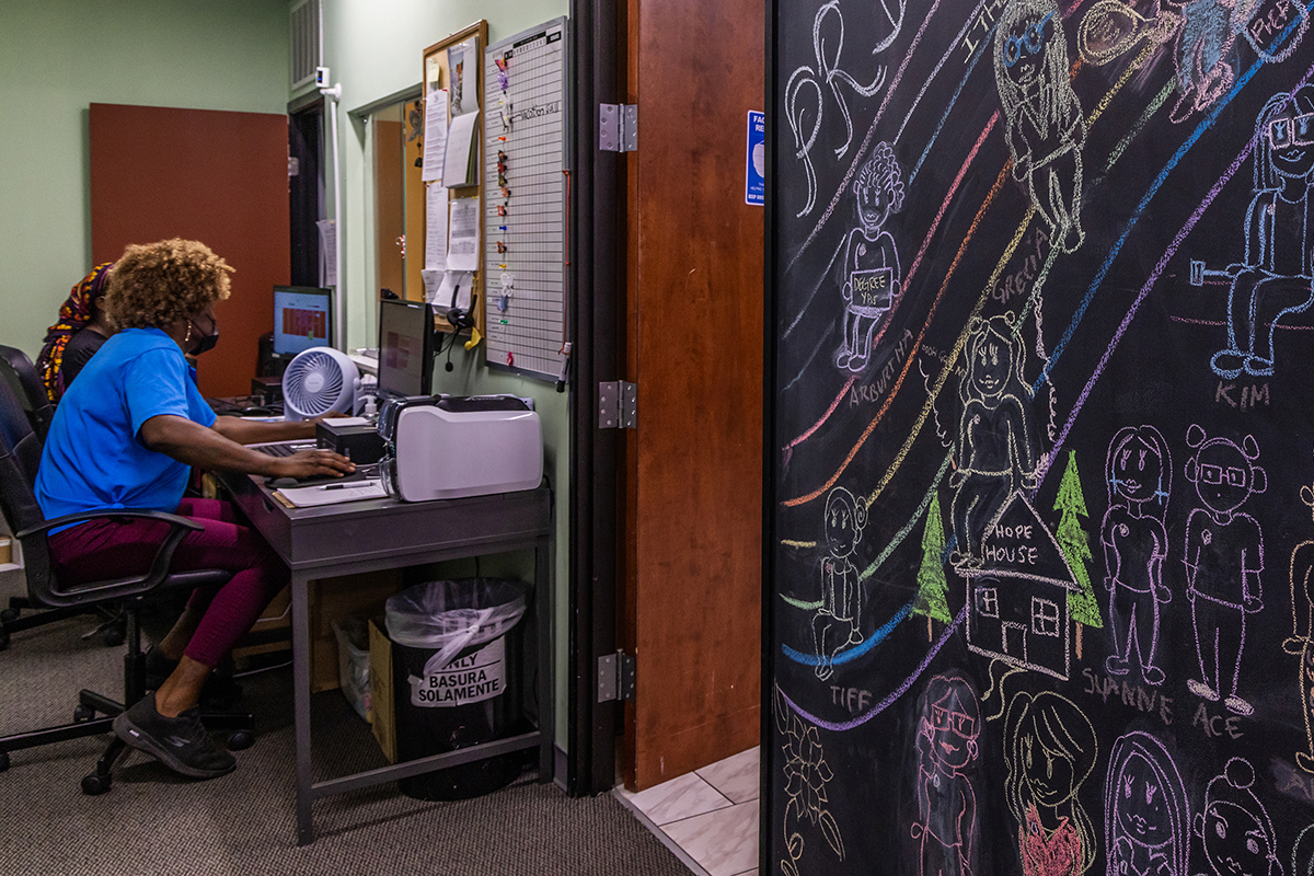 A chalkboard filled with drawings of staff and a large rainbow hangs near the front desk at the TransLatin@ Coalition office in Los Angeles on July 5, 2022. Jimena Sandoval, the group’s communications and marketing coordinator, says it was drawn for Pride Month. (Photo by Jessica Alvarado Gamez/News21)
