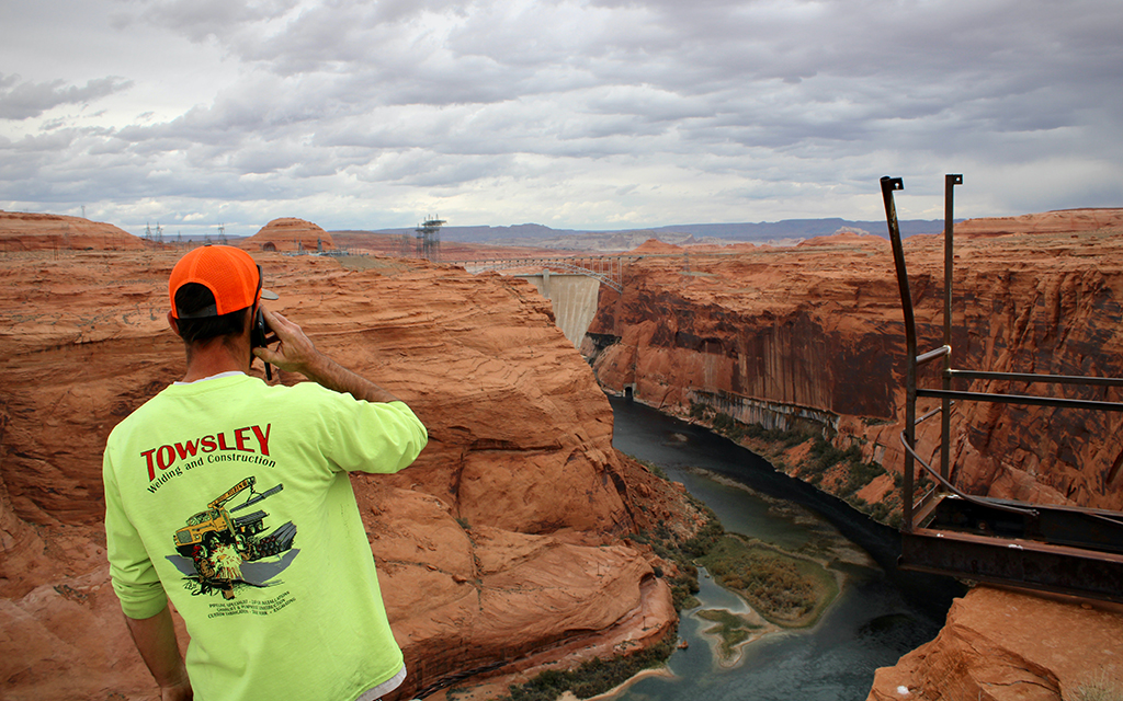 Tobyn Pilot of Page Utility Enterprises looks down toward Glen Canyon Dam. A pipe within the dam pulls water up to Page, but it needed modifications to keep operating amid dropping levels at Lake Powell. The city says it needs help funding a second pipe to provide longer-term water security. (Photo by Alex Hager/KUNC)