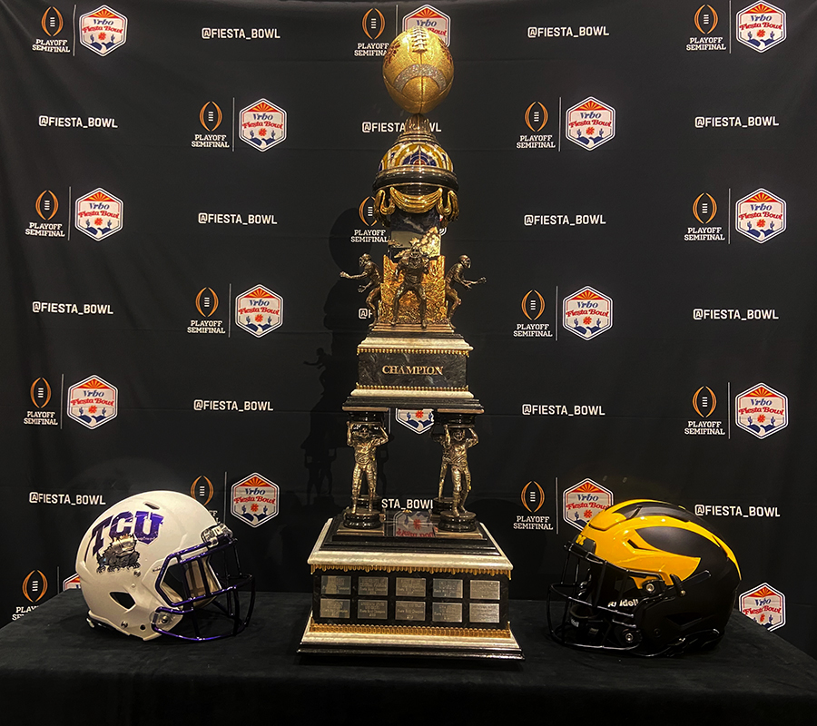 The Fiesta Bowl trophy sits between TCU and Michigan helmets at the Fiesta Bowl media day Thursday in Scottsdale. The trophy winner will be determined Saturday at State Farm Stadium in Glendale. (Photo by Nicholas Hodell/Cronkite News)