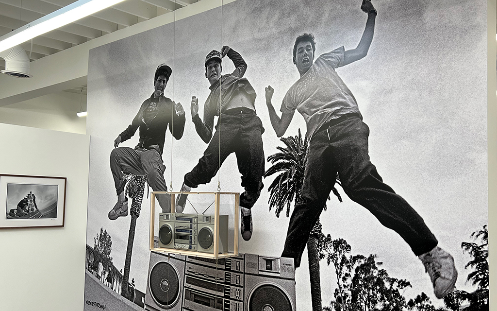 The authentic boombox, a device used to play music throughout the 1980s and 1990s shown in the Beastie Boys photo, is displayed in front of the image. Photographed on Jan. 19, 2023. (Photo by Daniel Ogas/Cronkite News)