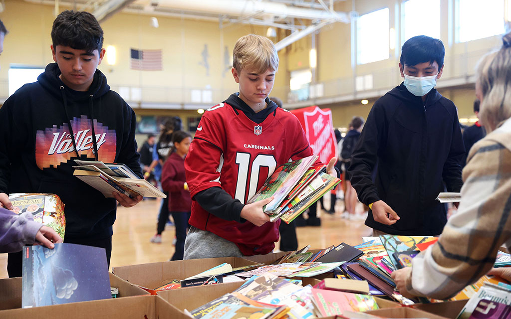 Dane Spratley, a Jack Barnes Elementary School student, helps organize donated picture books with his classmates. (Photo by Brooklyn Hall/Cronkite News)