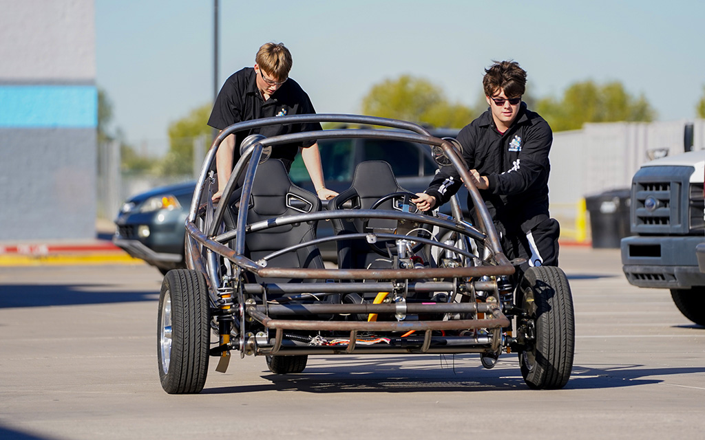Junior Ethan Lucas, left, and sophomore Aiden Bratton push an electric vehicle they’ve been building at Cactus High School in Glendale on Oct. 31, 2022. (Photo by Samantha Chow/Cronkite News)