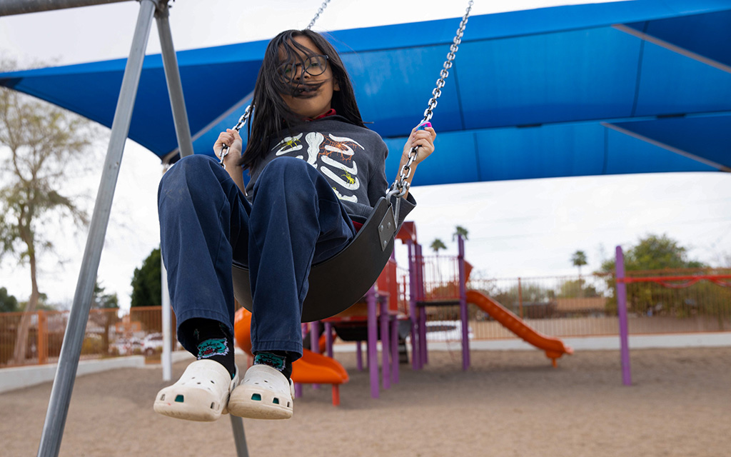 Daniel Chiago, 11, swings on the swing set at Loma Linda Elementary School in Phoenix while he waits for the new playground. He hopes there will be more swings on the new playground. Photo taken on Feb. 23, 2023. (Photo by Evelyn Nielsen/Cronkite News)