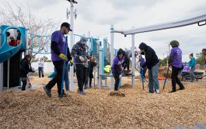 Volunteers rake mulch on the new playground at Loma Linda Elementary School in Phoenix on Feb. 23, 2023. (Photo by Evelyn Nielsen/Cronkite News)