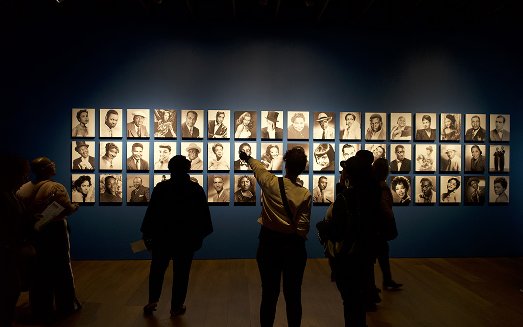 Museum guests point and admire the photos of iconic Black stars like Sidney Poitier and Hattie McDaniel. It was part of an exhibit on early Black films at the Academy Museum of Motion Pictures in a photo taken Feb. 4, 2023, in Los Angeles. (Photo By Ayana Hamilton/Cronkite News)