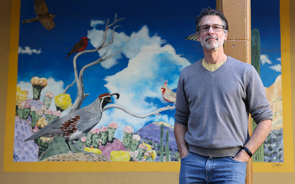 David Robinson, Tucson Audubon Society’s director of conservation advocacy and interim executive director, in front of the organization’s mural, “Desert Dreaming” by Jason Milici. Photo taken on Jan. 31, 2023, in Tucson. (Photo by Evelyn Nielsen/Cronkite News)