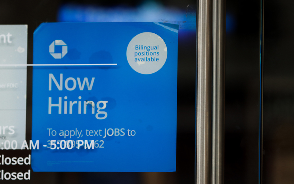 A now-hiring sign is posted at Chase Bank in downtown Phoenix on Feb. 21, 2023. Economists say the churn of people moving between jobs is driving up wages. (Photo by Logan Camden/Cronkite News)