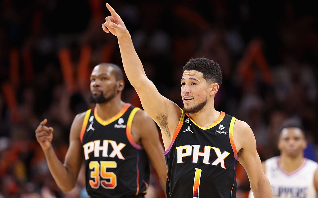 Devin Booker, right, points a finger to the sky and Kevin Durant walks beyond him in Crypto.com Arena.