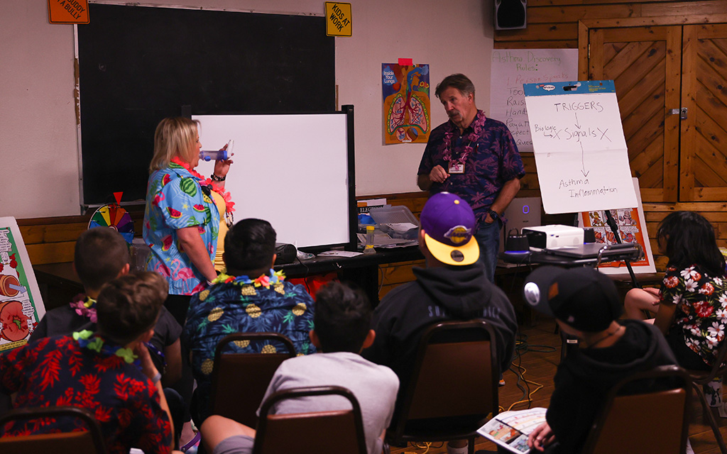 Ashley Feighery, camp vice president, left, helps Steve Fuchs lead a demonstration about how to use different types of inhalers at Camp Not-A-Wheeze in Heber, Arizona. (Photo by Joey Plishka/Cronkite News)