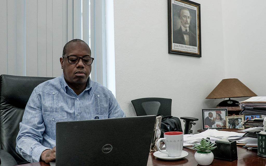 Victor Aquino, communications director for the Dominican Republic’s Ministry of Industry and Trade, working in his Santo Domingo office on March 6, 2023. (Photo by TJ L’Heureux/Cronkite Borderlands Project)