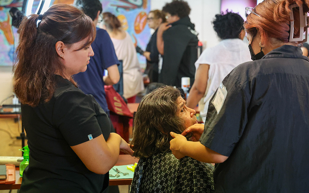 Mayra Idalgo and Kenia Arechiga cut Yolanda Morenos’ hair during the back-to-school event hosted at Chicanos Por La Causa on July 26, 2023. (Photo by Evelin Ruelas/Cronkite News)