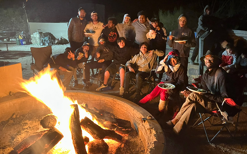 Boys and mentors enjoy their dinner around a campfire. (Photo courtesy of Boys to Men Tucson)