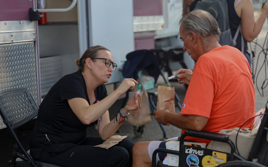  Medical coordinator Monica Rico provides additional testing kits to Douglas Walters at the Circle the City mobile clinic in Phoenix on Sept. 12, 2023. (Photo by Sam Volante/Cronkite News)
