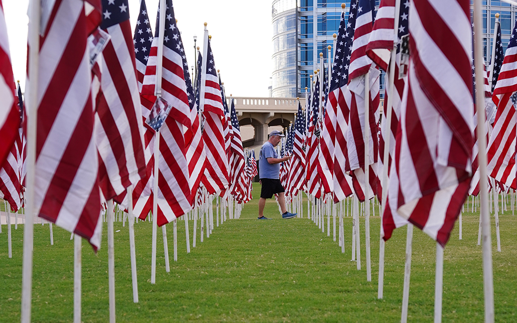 A visitor walks through rows of flags at the 9/11 Tempe Healing Field tribute at Tempe Beach Park, on Sept. 11, 2023. (Photo by Kiersten Edgett/Cronkite News)