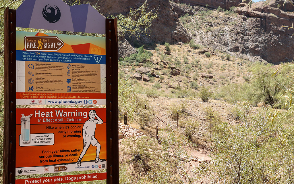 “Take a Hike, Do it Right” signs warn visitors to Phoenix popular hiking trails of the dangers while hiking in hot conditions. (File photo by Evelin Ruelas/Cronkite News)