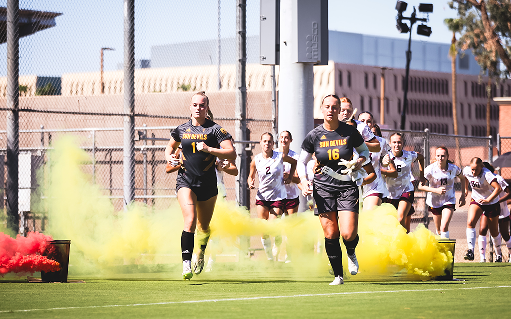 Two ASU Women's soccer players running onto the field.