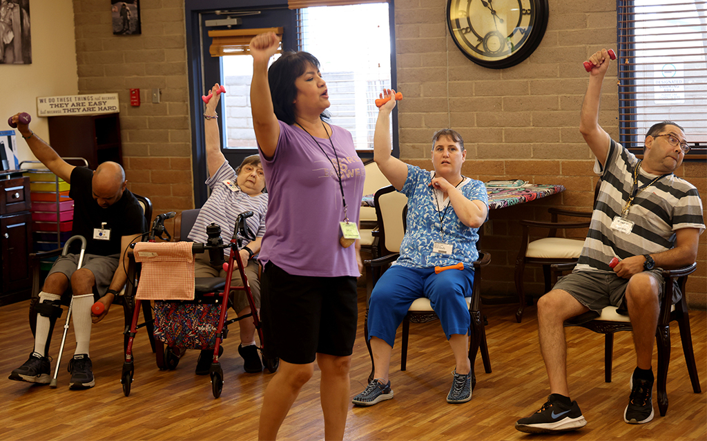 Kathleen Allen lifts light weights during an exercise activity at the FSL ReCreación Center on Sept. 13, 2023. Allen suffered a brain aneurysm at 22 years old. She receives day care five days a week. (Photo by Kevinjonah Paguio/Cronkite News)