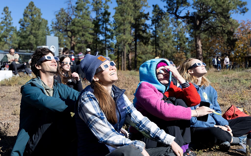 From left, Scott Glib, Laura Nicholson, Haley Finch and Emma Railey look at the annular solar eclipse with protective solar glasses at the Lowell Observatory in Flagstaff on Sat., Oct. 14, 2023. "We just thought people would be excited and knowledgeable here and it would be fun to share in the excitement," Nicholson said. (Photo by Emily Mai/Cronkite News)