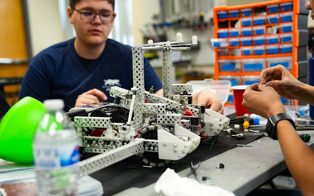 Desert Ridge student and a partially built robot.